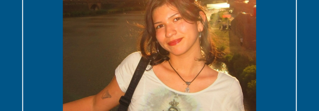 A young woman standing by an urban river