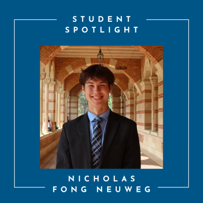 Young man in a dark suit, smiling, under the Royce Hall arches
