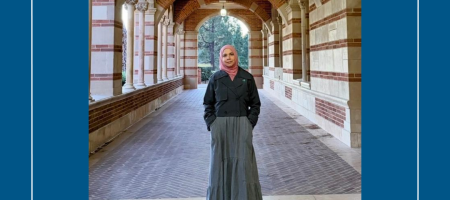 Young woman in hijab and dress stands in the UCLA Royce Hall arches