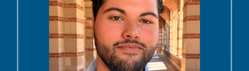 UCLA student with beard, standing in the Royce Hall arches.
