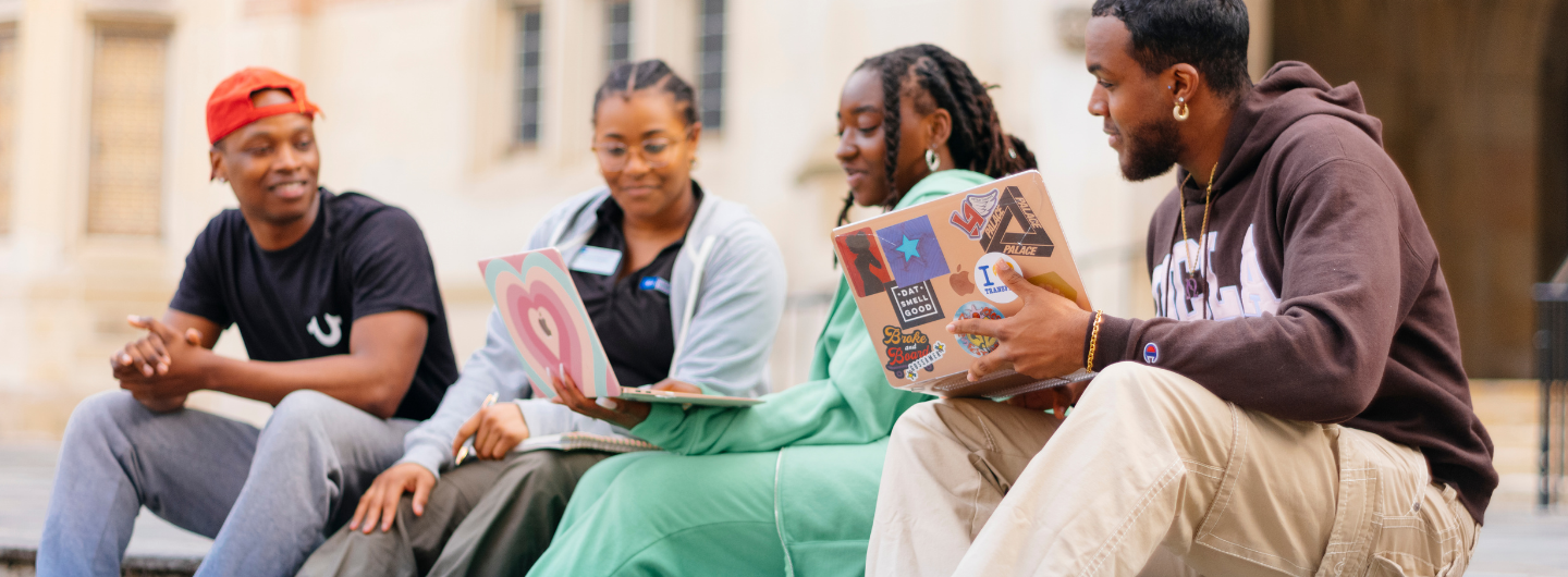 Four students sitting on steps and talking