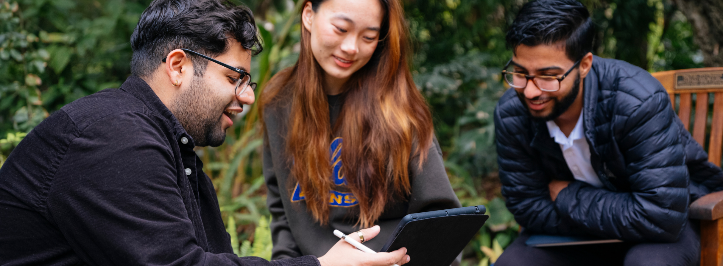 three students look at a tablet