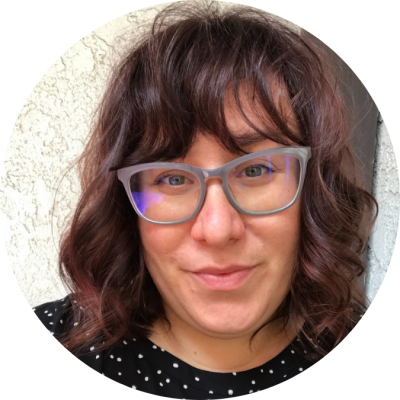 Jacquelyn Ardam headshot Woman with curly hair and glasses