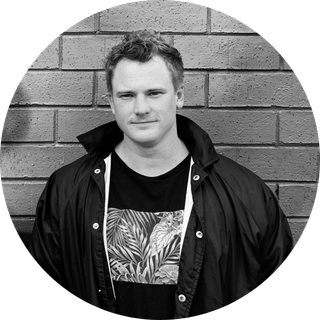 Man wearing a jacket standing in front of a brick wall