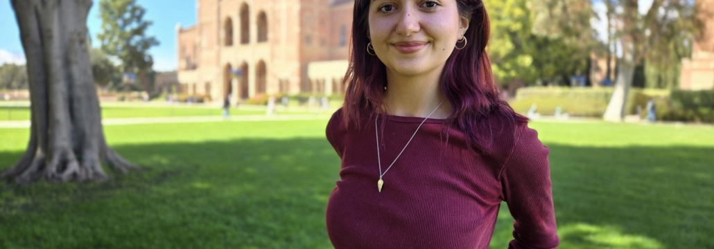 A woman stands on the lawn in front of Royce Hall