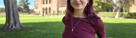A woman stands on the lawn in front of Royce Hall