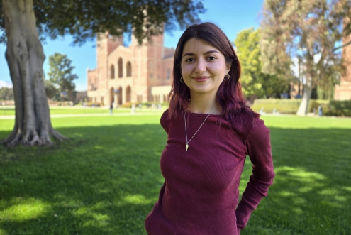 A woman stands on the lawn in front of Royce Hall